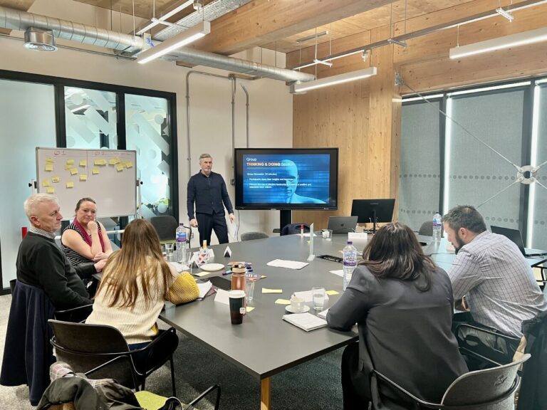 Engaged group of professionals in a boardroom, smiling and responding positively to the training with James Flemin
