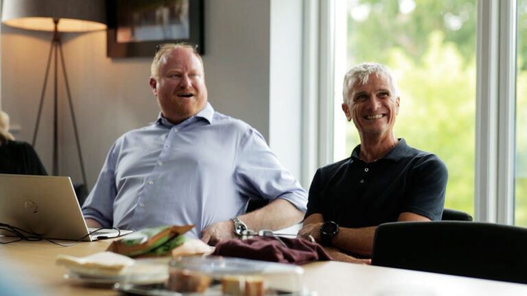 Participants in a boardroom actively listening and relating to the coach during an interactive training session.